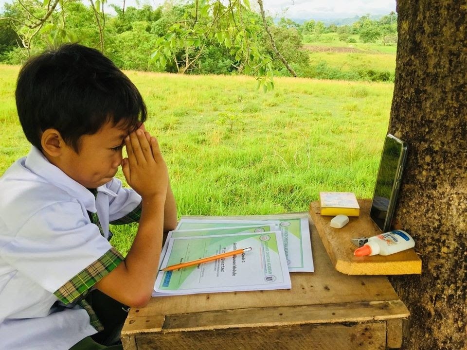 A young student in Bohol, Philippines is seen taking his lessons through a borrowed smartphone in a “tree house” his family built on top of a hill where the cell signal is strong enough